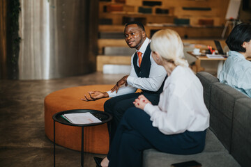 A candid conversation between two diverse individuals seated in a contemporary co working...