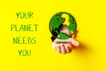 Hand holding a globe with the words Your planet needs you written below it