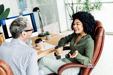 Two professionals engaging in a productive discussion while holding coffee cups in a modern and...