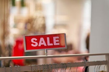 Schild mit der Aufschrift Sale an einem Kleiderständer in einem Geschäft für Bekleidung