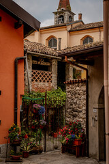  Charming Italian Alleyway with Stone Walls and Potted Flowers: Picturesque View of Colorful Architecture and Church Tower in a Historic Village Setting