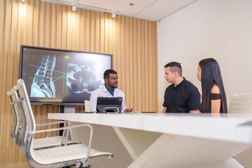 A doctor working with tablet computer to explain progressive of disease to patient and family in medical consultation room