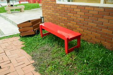 Red bench and red brick wall of house,rest chair in park or garden,colorful wooden bench and green grass.