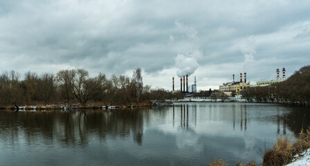 Industrial chimneys emit thick smoke into the winter sky, highlighting urban air pollution. A...