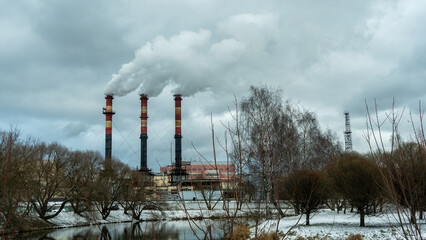 Industrial chimneys emit thick smoke into the winter sky, highlighting urban air pollution. A...