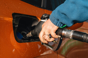Fueling up orange car at a modern gas station on a sunny day, capturing the essence of everyday...