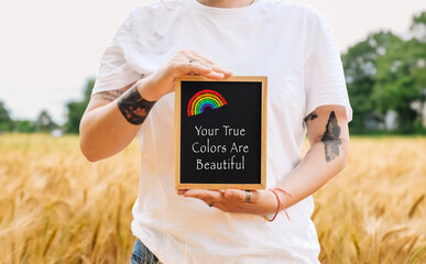 Woman holds a rainbow and a sign that says Your true colors are beautiful.