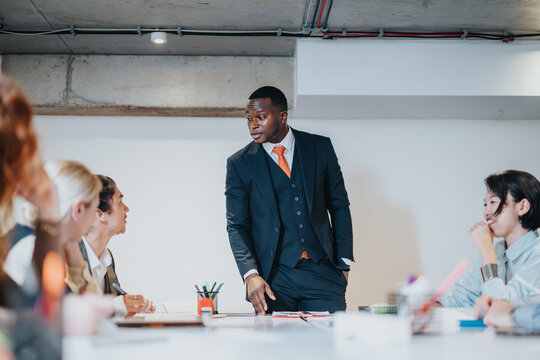 Team leader discussing plans in a professional office setting with a diverse group of colleagues around a table, fostering teamwork and collaboration
