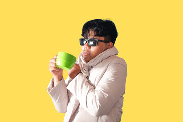 Stylish Man Enjoying a Warm Drink on a Yellow Background