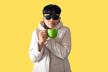 Stylish Man in White Coat Enjoying a Green Mug of Coffee on Yellow Background