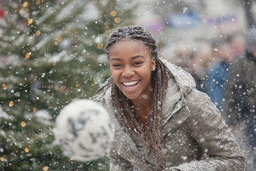 Joyful african female young adult enjoying winter snowfall outdoors