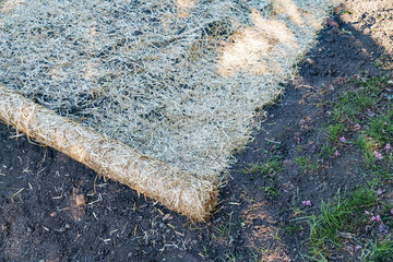 straw erosion control blanket. The bale is unrolled and covers the ground.