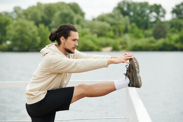 A young athletic man stretches on a railing by a tranquil lake, enjoying the outdoors