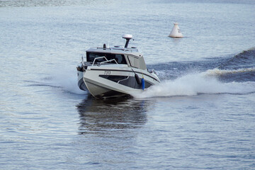 A speedboat glides across the water, creating waves, spray and foam.