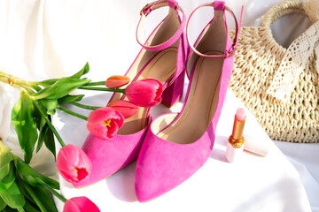 Pink high-heeled shoes with ankle straps on a white surface. Fashion and feminine elegance.