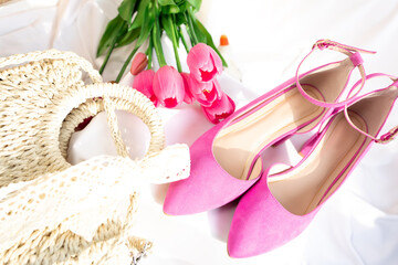 Pink high-heeled shoes with ankle straps on a white surface. Fashion and feminine elegance.