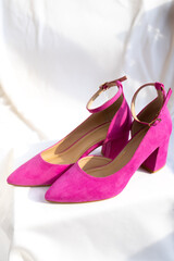 Pink high-heeled shoes with ankle straps on a white surface. Fashion and feminine elegance.