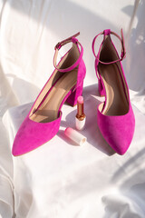 Pink high-heeled shoes with ankle straps on a white surface. Fashion and feminine elegance.