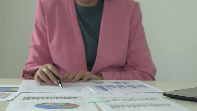 Real estate gent asian woman is reading and checking paper documents, signing the contract to send to her business partner. Concentrated smart ambitious lady is preparing research, remote freelancer.
