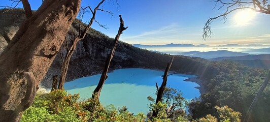 Stunning sunrise over Kawah Putih, West Java. This mesmerizing volcanic crater lake boasts turquoise waters, framed by lush hills and mystical fog. Perfect for nature lovers & travel photography.