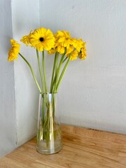 A clear glass vase with bright yellow flowers placed as a decoration on a table; suitable as home...