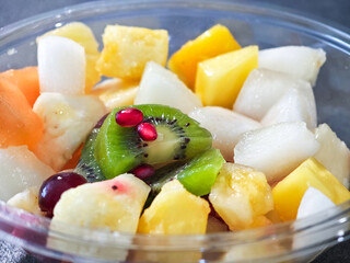 A bowl of fruit with a kiwi in the middle
