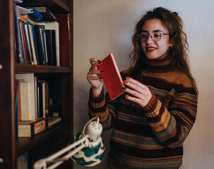 Friends enjoying time together in a homely library room, browsing and picking books from the shelf...