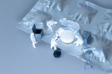 Creative conceptual image showing tiny figurines of forensic investigators examining a pill on an...