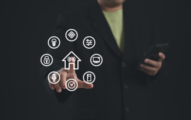 User touching smart home control interface with various IoT icons displayed around a digital house symbol, representing home automation, smart devices, and centralized control using mobile technology.