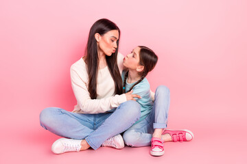 Happy young mother and daughter bonding together on pink background showing playful expressions and...
