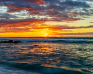 Vibrant Ocean Sunset with Dramatic Clouds and Gentle Waves