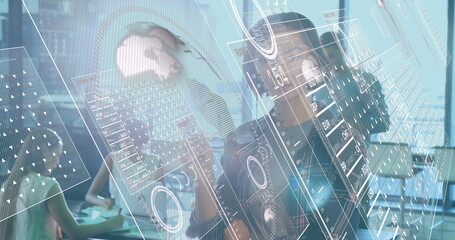 Collaborating team of four in smart attire analyzing holographic data panels in conference room