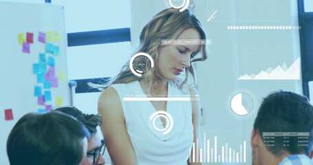 Reviewing data mid adult woman leading meeting in conference room, with sticky notes and graphs