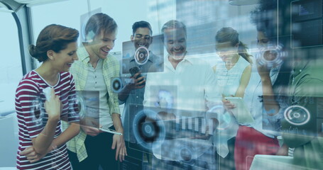 Team of seven professionals examining holographic panels in boardroom, with tablets phones laptop
