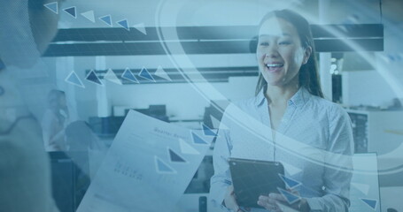 Smiling Korean woman holding tablet and receiving report in open office, with data graphics