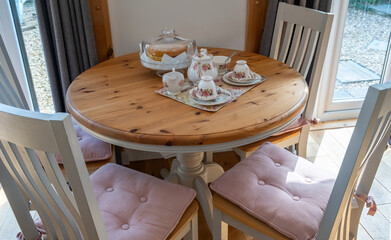 Bone china teapot, tea cups, milk jug and sugar bowl on a wooden table together with a Victoria...