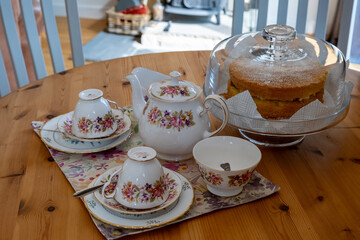 Bone china teapot, tea cups, milk jug and sugar bowl on a wooden table together with a Victoria...