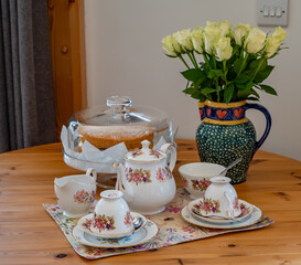Bone china teapot, tea cups, milk jug and sugar bowl on a wooden table together with a Victoria...