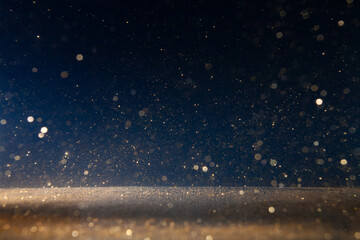 Sparkling golden particles drifting in the air against a dark background