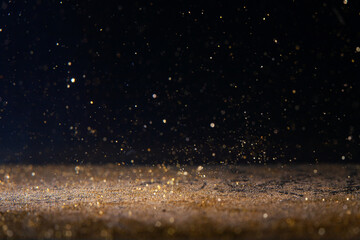 Sparkling golden particles drifting in the air against a dark background