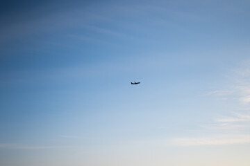 Silhouette of an airplane flying across a clear blue sky. Concept of air travel, global tourism, airline industry, and the freedom of modern transportation to distant destinations