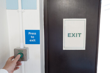Hospital medic seen pressing an exit button within a ward within an NHS hospital. The door leads to a non medical foyer.