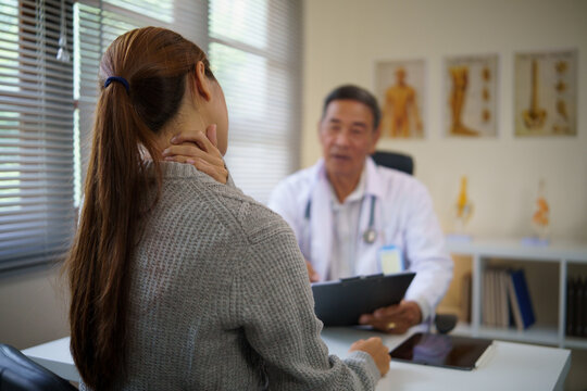 Patient experiencing neck pain consulting with a male doctor in a clinic. Health care concept.