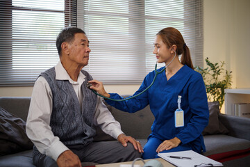 Female healthcare worker using a stethoscope to check the heart and lungs of a senior patient...