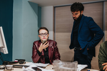 Office scene showing a team discussing work-related issues, capturing their focused and serious...