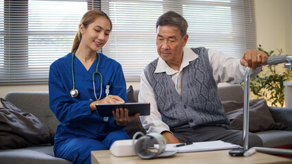 Female nurse showing health records to elderly man at home during routine checkup. Health care...