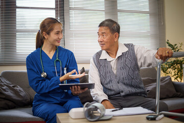 Female nurse showing health records to elderly man at home during routine checkup. Health care...