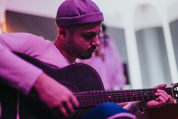 Focused musician playing acoustic guitar in a vibrant indoor setting