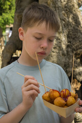 Young boy holding a tray of Italian castagnole, deep-fried sweet dough balls with jam, during an...