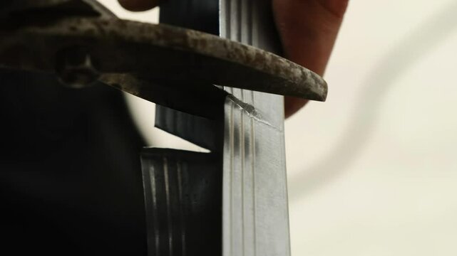 Worker holds metal panel making cuts with cutters at workshop closeup. Handyman prepares construction item for mounting plasterboard wall